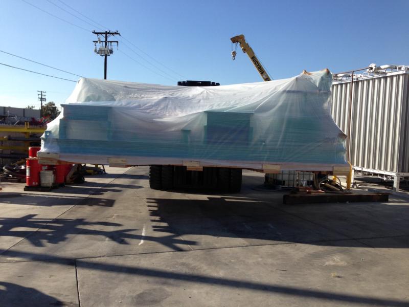 Large machinery covered with a tarp on a trailer at an industrial site