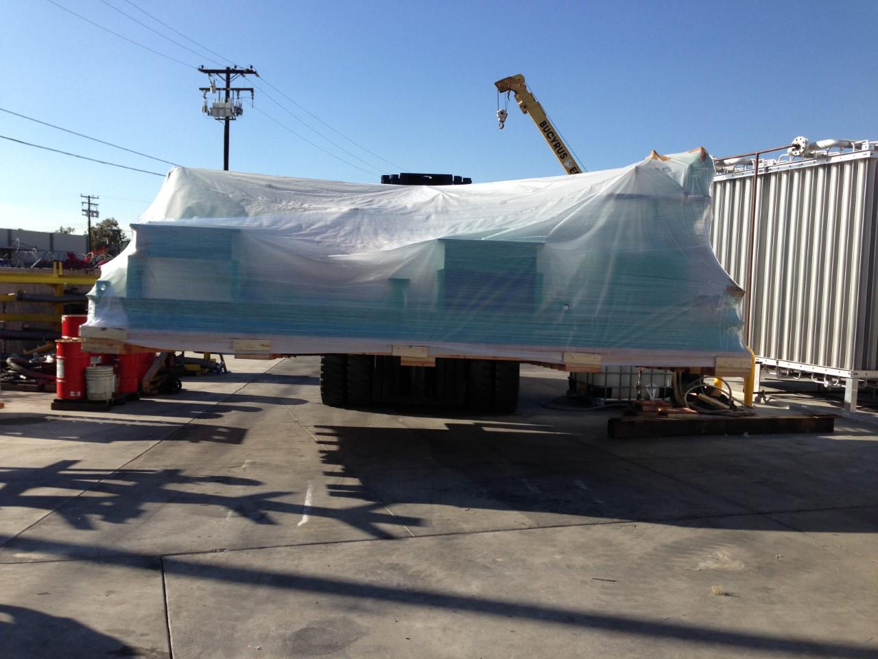 Large machinery covered with a tarp on a trailer at an industrial site Large machinery covered with a tarp on a trailer at an industrial site